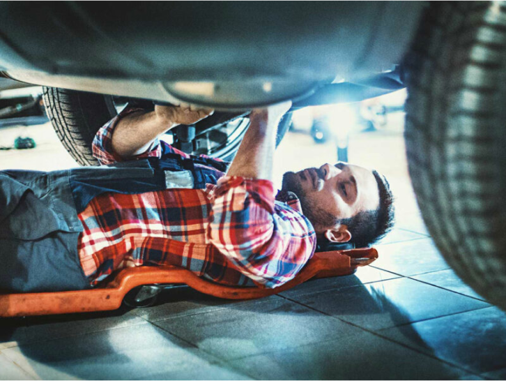 A man lies under a car and works