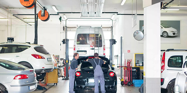 zwei Mitarbeiter überprüfen ein Auto in der Werkstatt