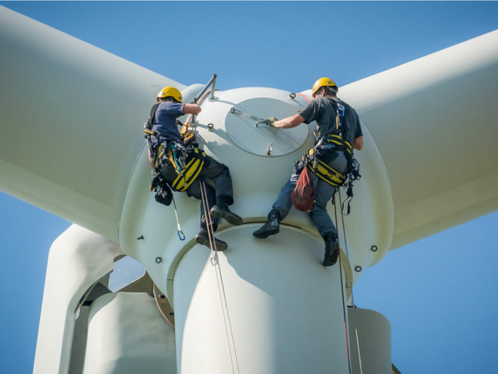 Zwei Männer arbeiten in der Höhe an einem Windkraftrad