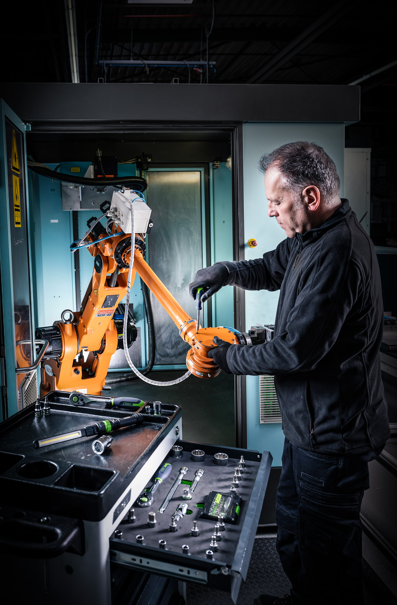 A man repairs a robot arm with Kukko tools