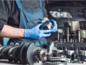 Two hands working on a metal part at a workbench